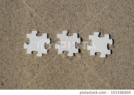 Three 3 wooden white puzzles copy space for your text on sandy beach. Summer vacation and holiday business travel concept. Jigsaw on the beach sand matching puzzle pieces together Template Mock up for 103386800