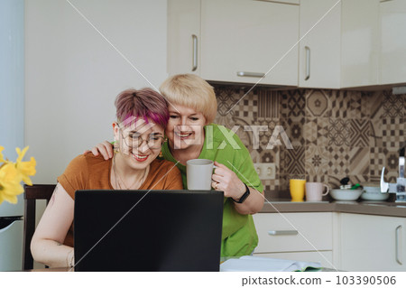 Adult mother and non-binary daughter communicate online with relatives laptop 103390506