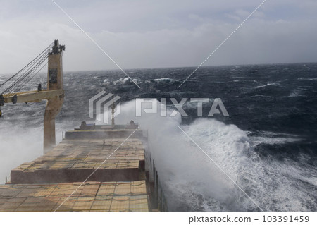 Cargo vessel with deck cargo at stormy sea. View from navigational bridge. Stormy sea, Bad weather. Gale. Rough sea. Cargo vessel with deck cargo at stormy sea. View from navigational bridge. Stormy sea, Bad weather. Gale. Rough sea. 103391459