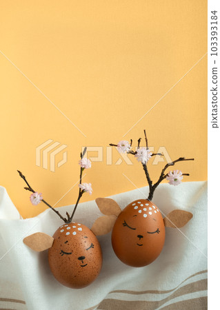 Funny deers made of eggs on fabric background. Brown Easter eggs. Space for your text. Yellow background. 103393184