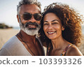 Middle age cuddling couple enjoying time on beach 103393326