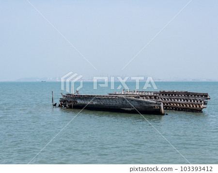 An abandoned wooden ship ran aground on the shore near the harbor. 103393412