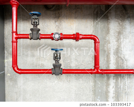 The red metal pipe and large valve of the fire fighting system. 103393417