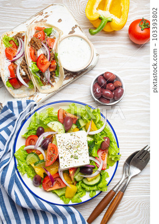 Traditional Greek Food: Greek Salad, Gyros with meat and vegetables, Tzatziki sauce, Olives on White rustic wooden table background from above. Cuisine of Greece 103393802