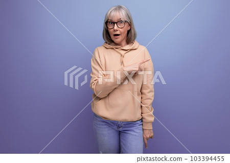 portrait of a surprised middle-aged woman in a sweatshirt on a studio background with copy space portrait of a surprised middle-aged woman in a sweatshirt on a studio background with copy space 103394455