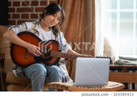 Young asian girl playing the guitar at home 103395413