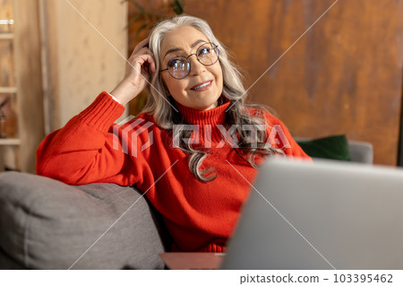 Woman in red shirt watching something on laptop 103395462