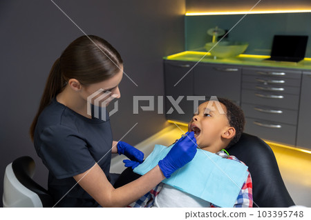 Female doctor checking up dark-skinned boy 103395748