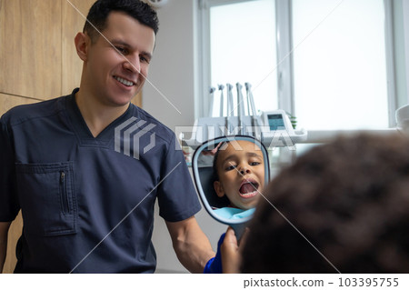 Doctor giving mirror to dark-skinned boy 103395755