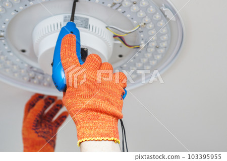 An electrician installs a chandelier on the ceiling. 103395955