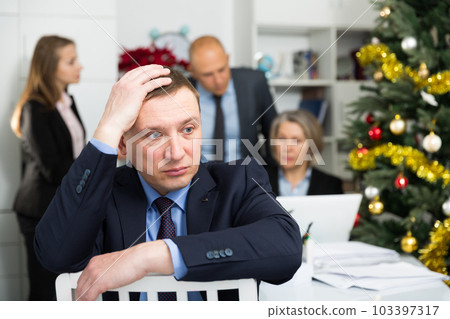 Business team tensely solving problems in office with offended man foreground Business team tensely solving problems in office with offended man foreground 103397317