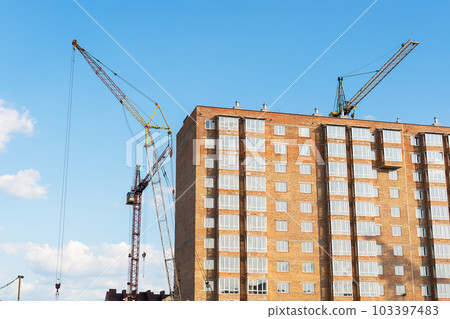 The construction of a new apartment building, against the background of the blue sky, a high-rise construction crane. 103397483