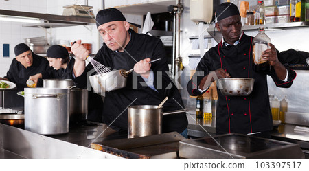 Chef with team preparing food in kitchen of restaurant 103397517