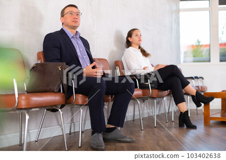 Middle-aged male visitor sitting on the bench in waiting room of clinic 103402638