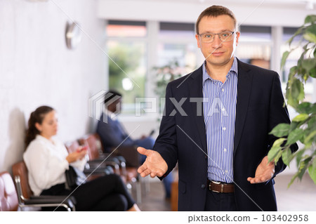 Confident middle-aged man standing with his back to waiting room Confident middle-aged man standing with his back to waiting room 103402958