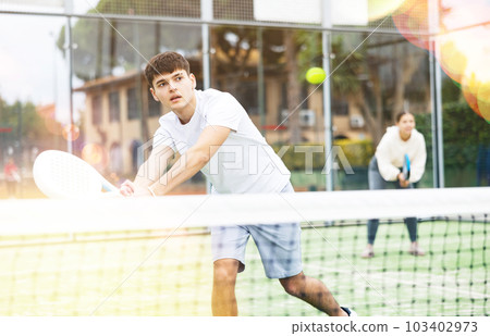 Young focused guy playing paddle tennis outdoors Young focused guy playing paddle tennis outdoors 103402973