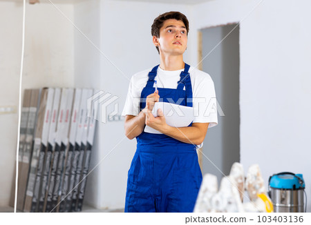 Young builder making checklist while planning indoor building overhaul Young builder making checklist while planning indoor building overhaul 103403136
