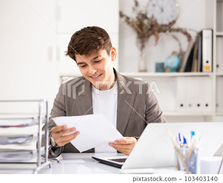 Male bookkeeper doing paperwork in workplace in office - checks accounting documents Male bookkeeper doing paperwork in workplace in office - checks accounting documents 103403140