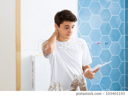 Confused young designer determining scope of work in apartment during refurbishment Confused young designer determining scope of work in apartment during refurbishment 103403143