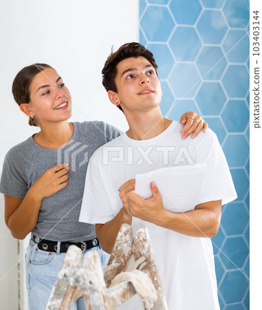 Young couple with documents checks the number of tiles, making important notes Young couple with documents checks the number of tiles, making important notes 103403144