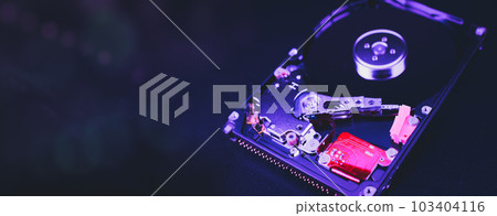 An open hard disk disassembled HDD of a computer or laptop lies on a purple surface. Computer hardware and accessories. Hard disk storage. 103404116