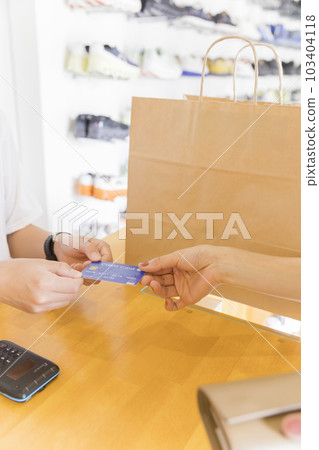 一個年輕女人在鞋店買鞋並用信用卡付款的手 103404118