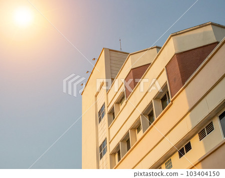 side view of yellow concrete building Intersect the orange sun. 103404150