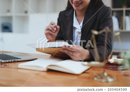 Young lawyer in office Business woman and lawyers discussing contract papers with brass scale on wooden desk in office. Law, legal services, advice, Justice and real estate concept 103404599