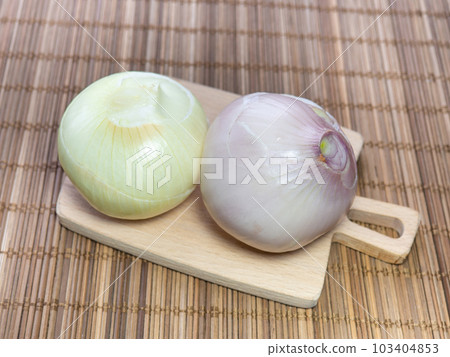 Two peeled onions on a small cutting board. Root crop before cooking dinner. Spicy vegetable. Useful product. Two peeled onions on a small cutting board. Root crop before cooking dinner. Spicy vegetable. Useful product. 103404853