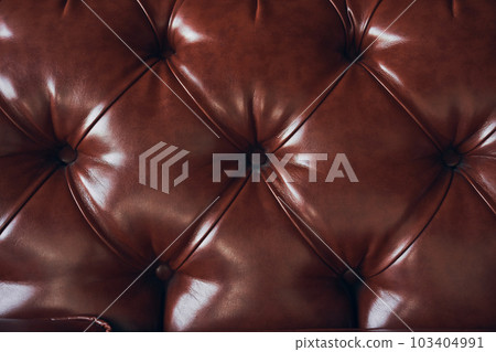 Faux brown leather close-up, upholstered furniture in retro Chesterfield style with deep diamond pattern and buttons. High quality photo Faux brown leather close-up, upholstered furniture in retro Chesterfield style with deep diamond pattern and buttons. High quality photo 103404991