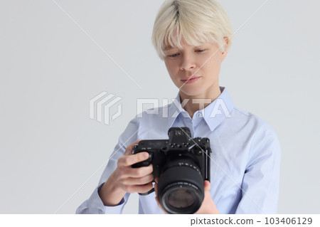 Short haired blonde woman adjusts digital photo camera Short haired blonde woman adjusts digital photo camera 103406129
