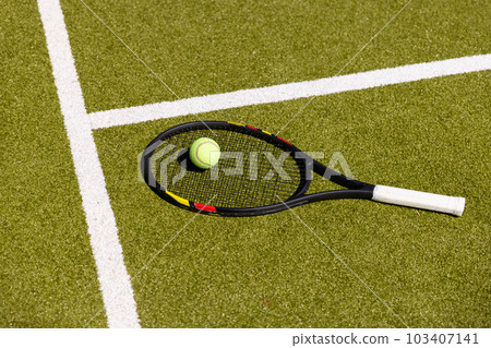 High angle view of tennis racket and ball by white marking on grassy field at tennis court High angle view of tennis racket and ball by white marking on grassy field at tennis court 103407141