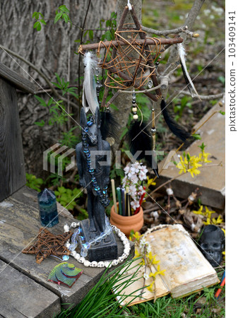 Anubis statue, magic book of spell and pentagram on witch altar. Occult, esoteric and divination still life. Mystic outside background with vintage objects Anubis statue, magic book of spell and pentagram on witch altar. Occult, esoteric and divination still life. Mystic outside background with vintage objects 103409141