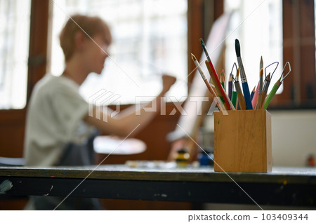 Close-up image of a pencil stand with various pencils and painting tools on a table Close-up image of a pencil stand with various pencils and painting tools on a table 103409344