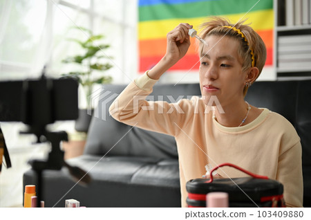A happy young Asian gay man applies facial essential serum to his face A happy young Asian gay man applies facial essential serum to his face 103409880