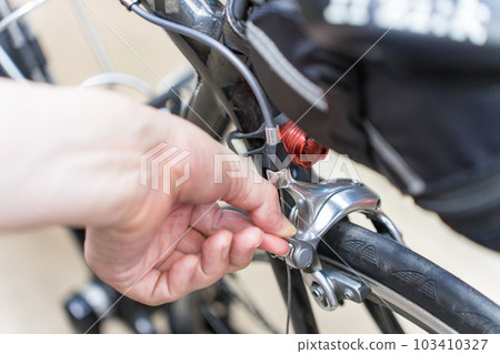 Opening and tightening the quick release lever of the rear brake of a road bike 103410327