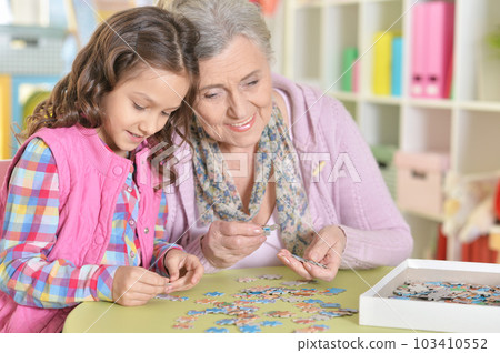 Grandmother with little granddaughter collecting puzzle 103410552