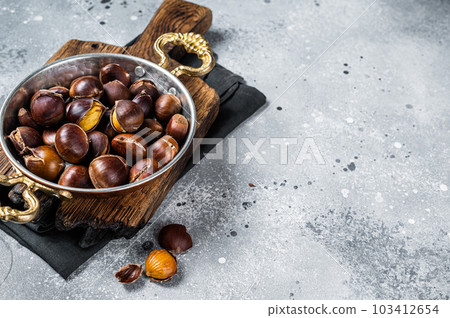 Cracked roasted chestnuts served in a skillet. Gray background. Top view. Copy space Cracked roasted chestnuts served in a skillet. Gray background. Top view. Copy space 103412654