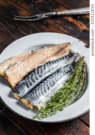 Salty sliced mackerel fillet fish in a plate with herbs. Wooden background. Top view 103412659