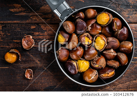 Roasted chestnuts nuts in a pan. Wooden background. Top view 103412676