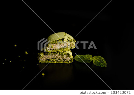 Artfully Served: Two Halves of Cut Green Macaroon with Mint on Dark Background 103413071