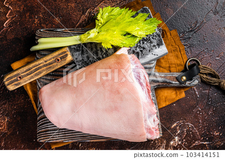 Fresh Raw pork shank knuckle on a butcher board with herbs for cooking. Dark background. Top view 103414151