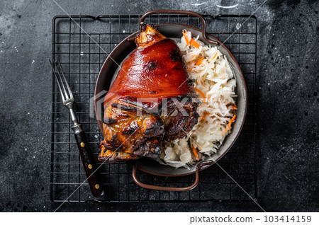 Traditional German cuisine Roasted pork knuckle Schweinshaxe with Sauerkraut. Black background. Top view Traditional German cuisine Roasted pork knuckle Schweinshaxe with Sauerkraut. Black background. Top view 103414159