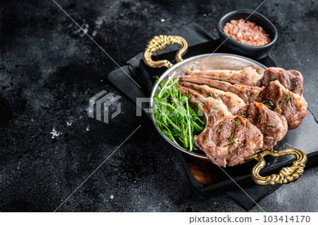 Grilled Lamb mutton Chops steaks in a skillet with green salad. Black background. Top view. Copy space 103414170