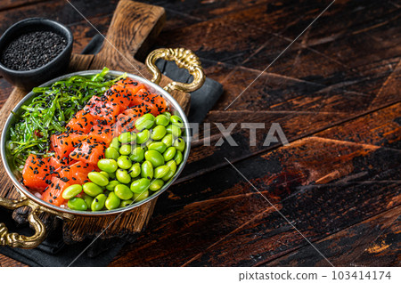 Salmon poke bowl with fresh fish, rice, seaweed, edamame, black sesame. Wooden background. Top view. Copy space Salmon poke bowl with fresh fish, rice, seaweed, edamame, black sesame. Wooden background. Top view. Copy space 103414174