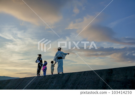 黃昏時分，穿著浴衣的一家四口在防波堤上玩耍 103414250