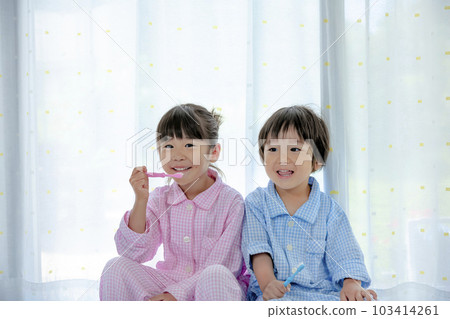 Sister and brother brushing teeth in pajamas 103414261