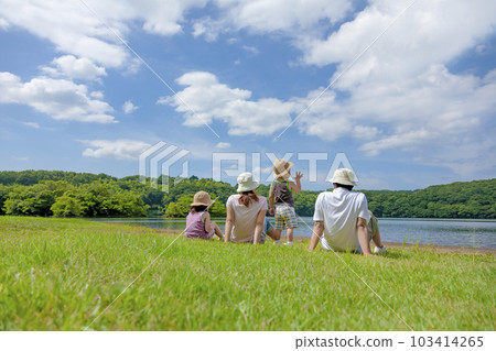 Back view of a family of four playing on the lakeside of a travel destination 103414265