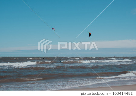 Wing Foiling kitesurfing wind surfing water outdoor sport in Baltic sea Dark blue clouds ocean water surface with foam waves before storm, dramatic seascape 103414491