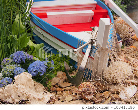 Installation on a marine theme, boat, anchor, nets. Details of the garden interior, marine-style decoration. 103415196
